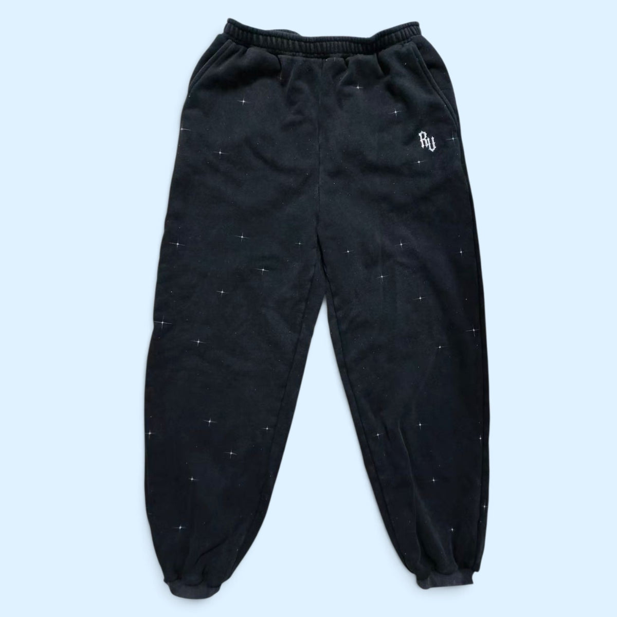 Rage U Athletics StarFall sweatpants — black heavyweight cotton fleece joggers with white star speckle print and embroidered RU logo on the left thigh